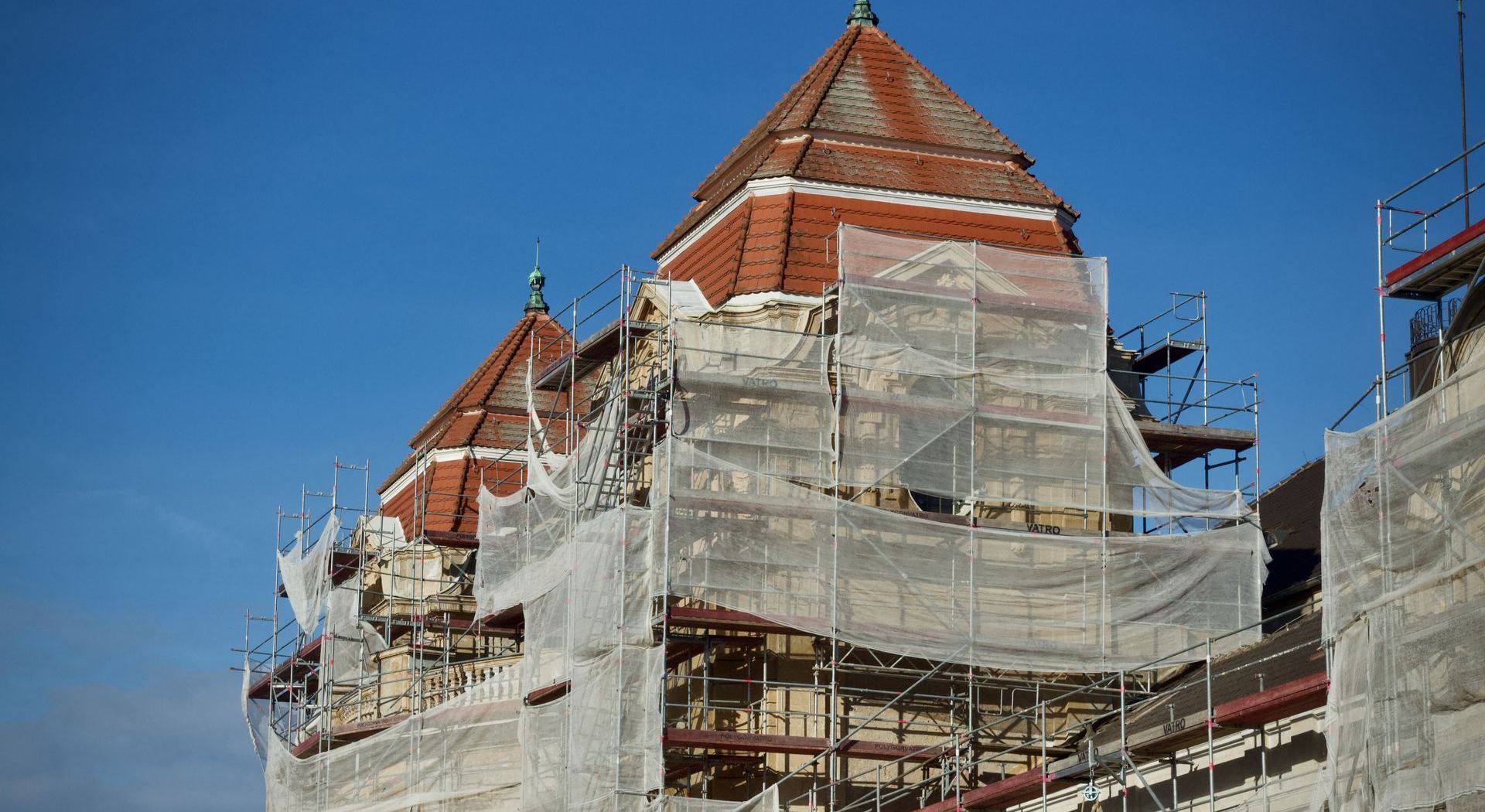 Bâtiment ancien sous échafaudage et filets pendant la réfection de sa toiture