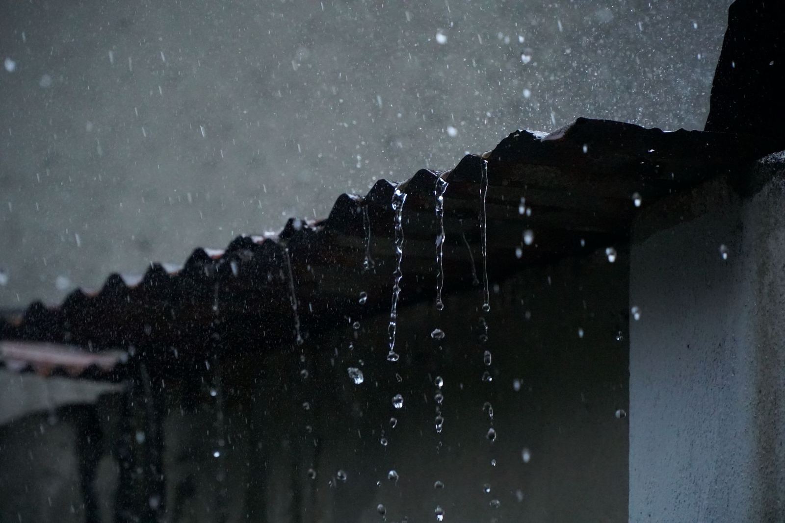 Pluie ruisselant en nappe depuis le bord d’une toiture