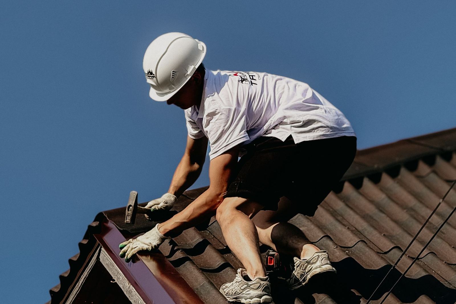 Couvreur reprenant le rampant d’une toiture, ciel dégagé